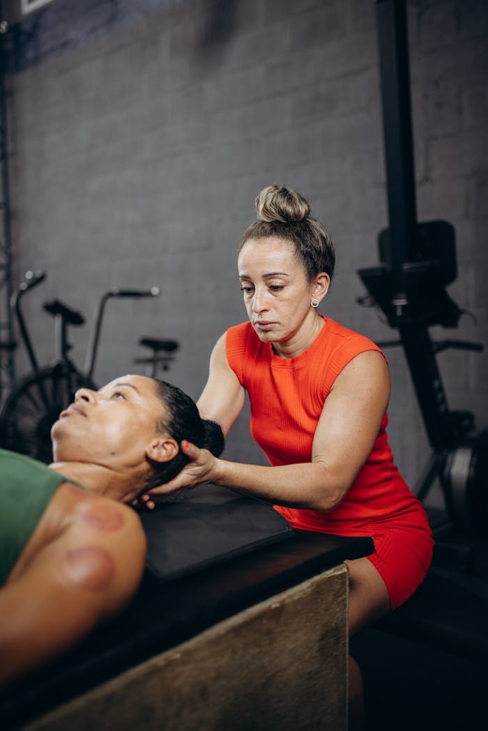 A therapist performs manual therapy on a client during a rehabilitation session in a gym.
